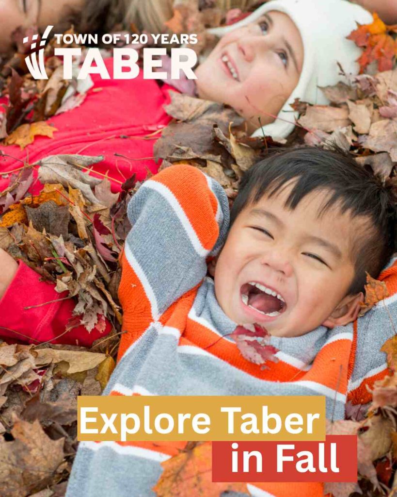 The children are lying on dry leaves, as a way to highlight Explore Taber in Fall.